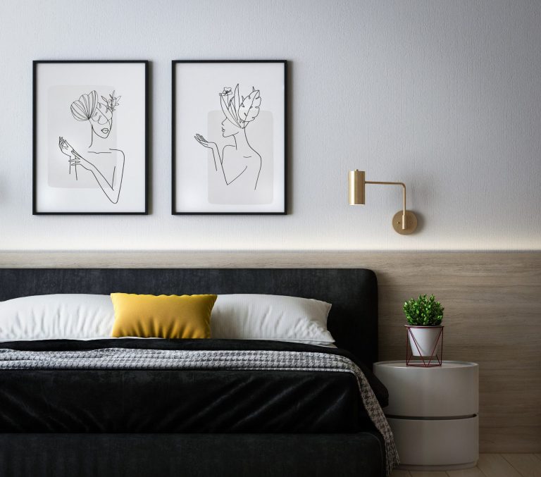 Modern bedroom featuring framed line art, a black bed with a yellow cushion, and a plant.